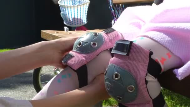 Mutter hilft ihrer Tochter, schützende Knieschoner zu tragen — Stockvideo