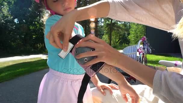 Η μητέρα βοηθά την κόρη της να φορούν προστατευτικά αγκώνα μαξιλαράκια και γάντια — Αρχείο Βίντεο