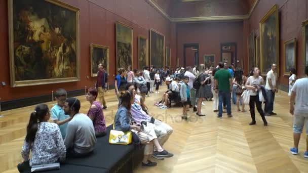 Mucha gente aprecia las pinturas y estatuas en el Museo del Louvre en París, Francia . — Vídeo de stock