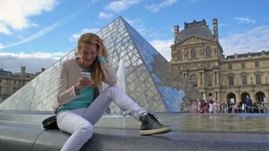 Mutlu kadın Selfie yapma bir Smartphone Paris Louvre de kullanır.
