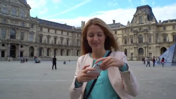 Happy Woman Making Selfie utiliza un teléfono inteligente en el Louvre de París — Vídeos de Stock