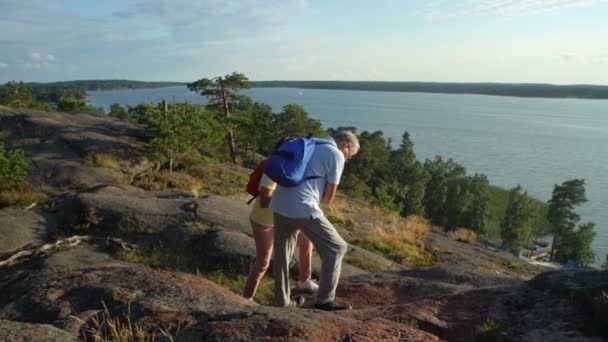 Ältere aktive Paar klettert auf den Felsen und bewundert den Sonnenaufgang, den Sonnenuntergang. — Stockvideo