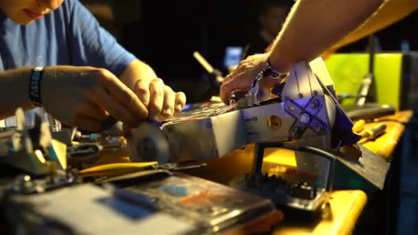 Två ingenjörer reparera en radiostyrd robot innan slaget robotar. — Stockvideo
