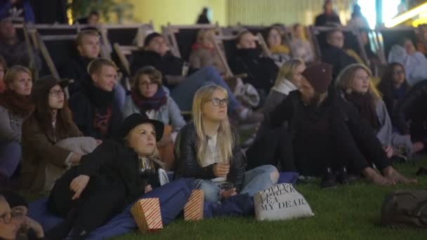 Багато глядачів у кінотеатрі на відкритому повітрі у вечірній час. — стокове відео