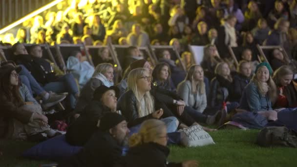 A lot of spectators in the movie theater outdoors in the evening. — Stock Video