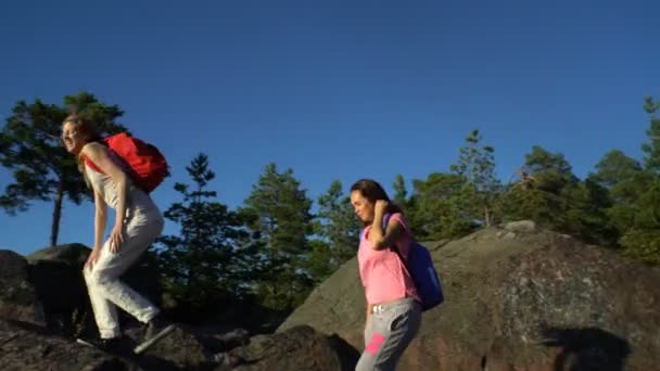 Twee actieve jonge vrouwen helpen elkaar te klimmen van een hoge rots — Stockvideo