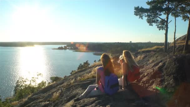 Gelukkige vrouwelijke paar Champagne drinken op een hoge rots in de zon — Stockvideo