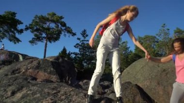 İki aktif genç kadınlara yüksek bir kaya tırmanmaya yardım