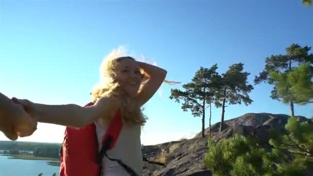 Молодая женщина, ведущая мужчину, чтобы забраться на высокую скалу . — стоковое видео