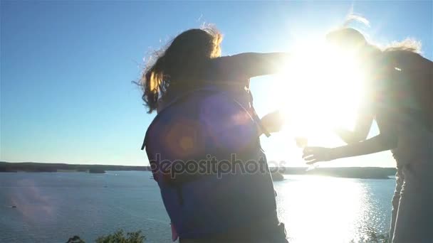 Pareja feliz bebiendo champán en una roca al sol — Vídeo de stock