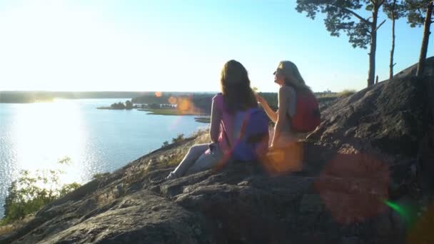 Glückliches weibliches Paar trinkt Champagner auf einem hohen Felsen in der Sonne — Stockvideo