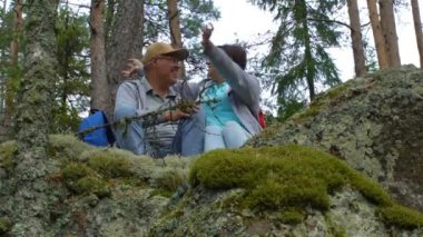 Kayanın üzerinde oturan ve Kuzey orman hayran yaşlı aktif Çift.