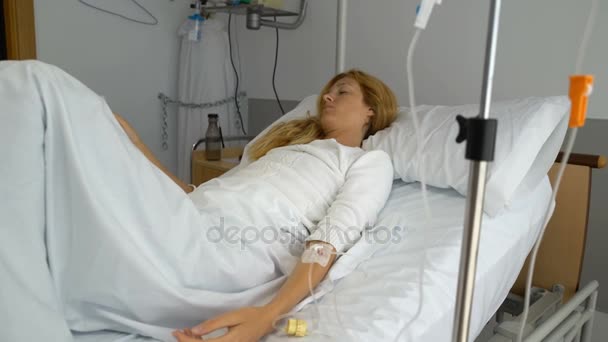 Uma paciente do sexo feminino em uma enfermaria de hospital com um gotejamento — Vídeo de Stock