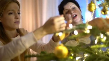 Olgun anne ve yetişkin kızı kapalı Noel ağacı süslemeleri.