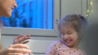 Genç anne ve küçük kızı un ile oynamak.