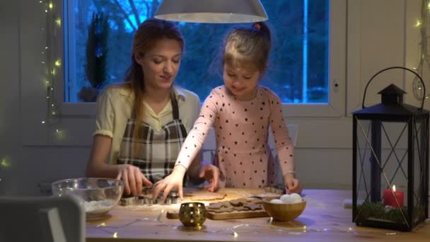 Молодая мать и ее маленькая дочь готовят рождественское печенье — стоковое видео