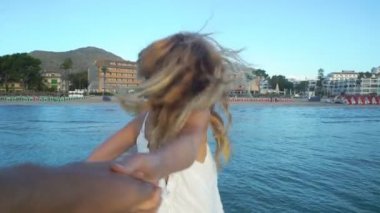 Elini tutarak ve onun arkadaşı iskelede önde gelen beyaz elbise giyen güzel genç kadın