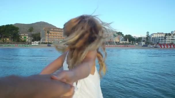 Schöne junge Frau in weißem Kleid hält Hand und führt ihre Freundin auf Pier — Stockvideo