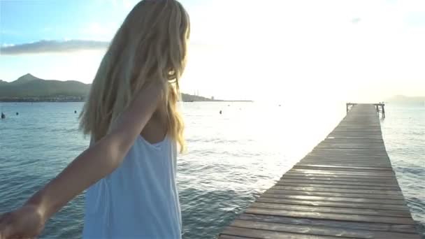 Красивая молодая женщина в белом платье держит за руку и ведет своего друга на пирс — стоковое видео