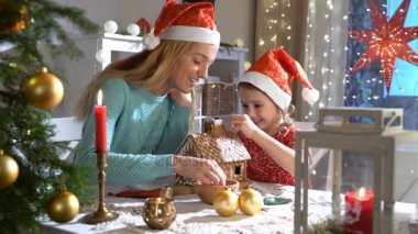 Genç anne ve kırmızı şapkalı kurabiye evi birlikte inşa etmek çok güzel kız.