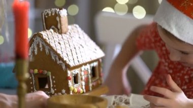 Genç anne ve kırmızı şapkalı kurabiye evi birlikte inşa etmek çok güzel kız.