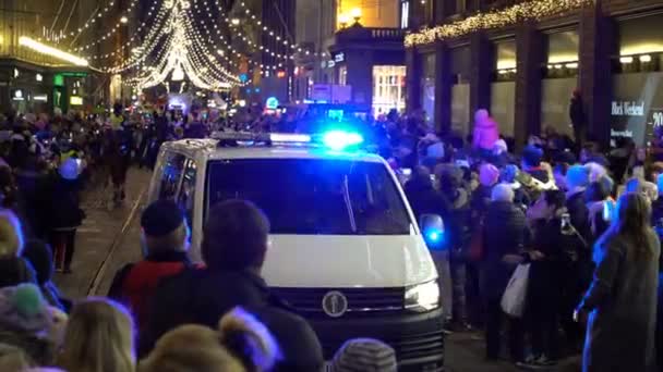 Coche de policía con luces intermitentes moviéndose lentamente entre la multitud festiva — Vídeos de Stock