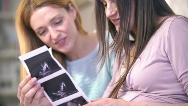 Pregnant woman and her friend consider photo 3D ultrasound Baby in the womb. — Stock Video