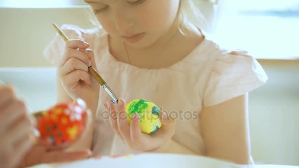 Young mother and her little daughter wearing Bunny ears coloring easter eggs — Stock Video