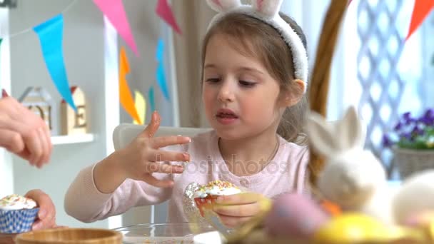 Joven madre y su hija con orejas de conejo cocinando cupcakes de Pascua — Vídeo de stock