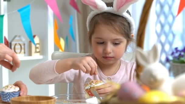 Jovem mãe e sua filha vestindo orelhas de coelho cozinhar cupcakes de Páscoa — Vídeo de Stock