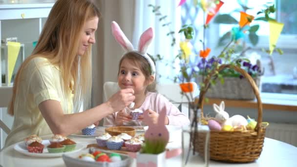 Giovane madre e sua figlia indossando orecchie di coniglio cucinare cupcake di Pasqua — Video Stock