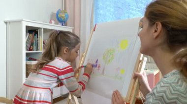 Küçük kızı ve annesi ile renkli kalemler çekiyor.