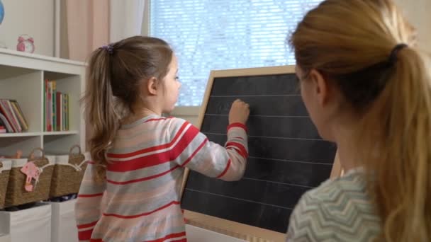 Jeune mère expliquant arithmétique à mignonne petite fille à la maison — Video