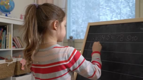 Молодая мать объясняет арифметику милой маленькой дочери дома — стоковое видео