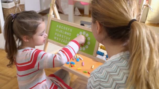 Frühkindliche Entwicklung. Kleines Mädchen lernt Zeit mit Uhrenspielzeug zu Hause — Stockvideo