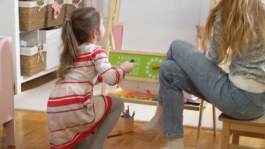 Küçük kızı ve annesi ile renkli kalemler çekiyor.