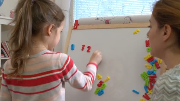 Jeune mère expliquant arithmétique à mignonne petite fille à la maison — Video