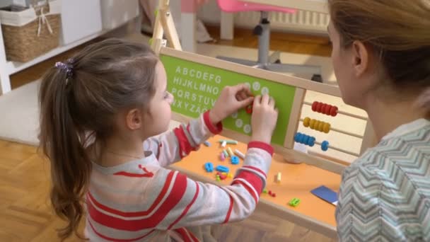 Desarrollo de la primera infancia. Niña aprendiendo tiempo con reloj de juguete en casa — Vídeo de stock