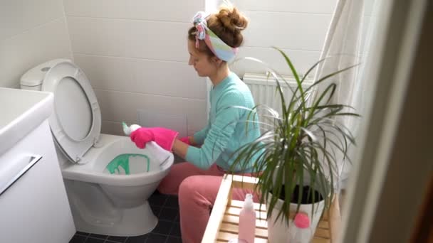 Mulher com uma luva de borracha limpa um vaso sanitário — Vídeo de Stock