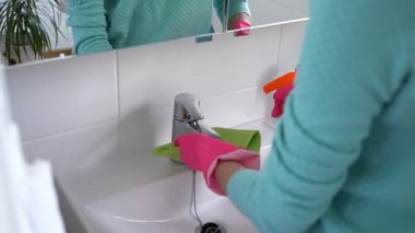 Kadın bir lastik eldiven ile banyo ve kamera gülümser bir lavabo temizler