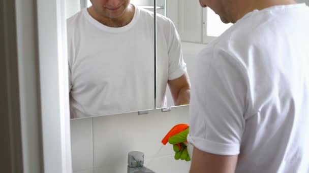 Hombre con un guante de goma limpia un lavabo en el baño — Vídeo de stock