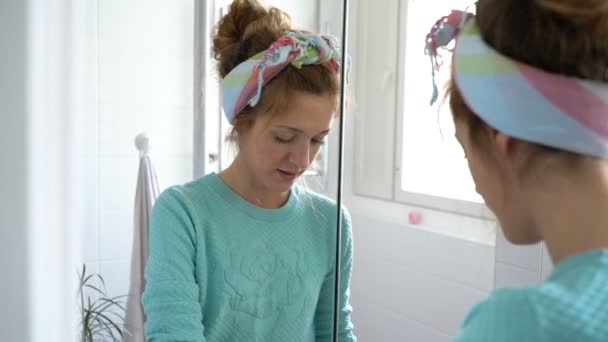 Frau mit Gummihandschuh putzt Waschbecken im Badezimmer und lächelt in die Kamera — Stockvideo