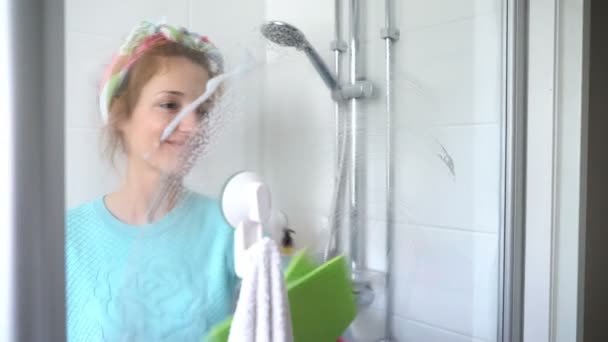 Woman with a rubber glove cleans a shower stall — Stock Video