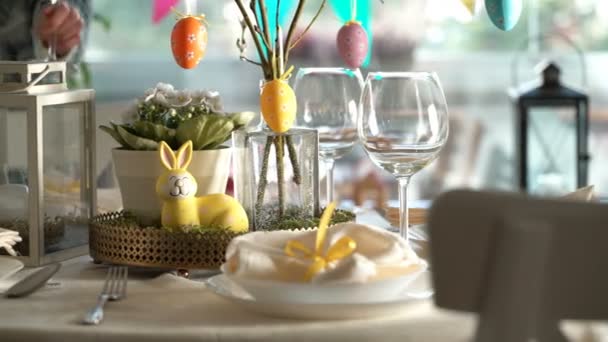 Young woman setting easter festive table with bunny and eggs decoration