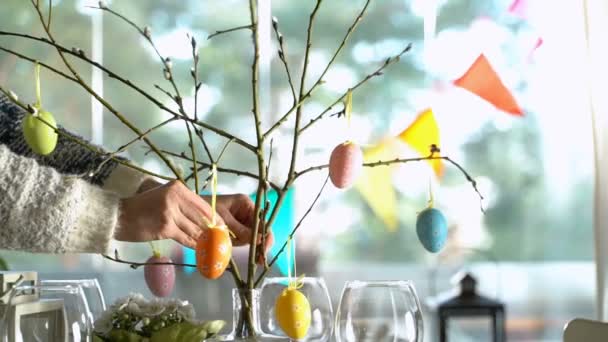 Молодая женщина накрывает пасхальный праздничный стол с украшением из кролика и яиц — стоковое видео