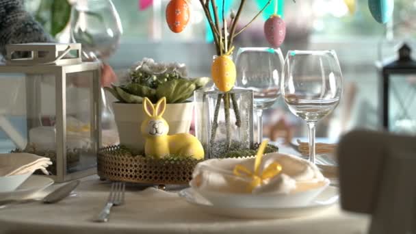 Young woman setting easter festive table with bunny and eggs decoration