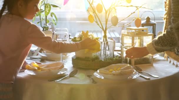 Kvinnan och hennes lilla dotter ställer påsk festbordet med påskhare och ägg dekoration — Stockvideo