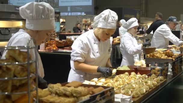 Los chefs preparan muestras de comida y tratan a los visitantes durante el Food Show — Vídeos de Stock