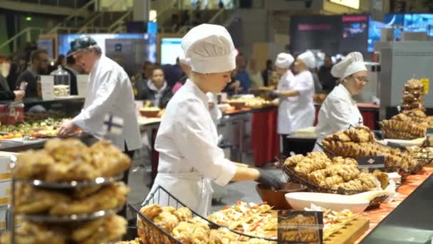 Шеф-повара готовят образцы продуктов питания и лечат посетителей во время выставки — стоковое видео