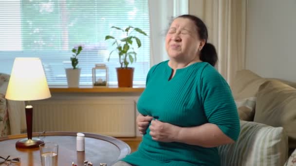 Starší žena trpí bolest břicha doma a bere prášky — Stock video